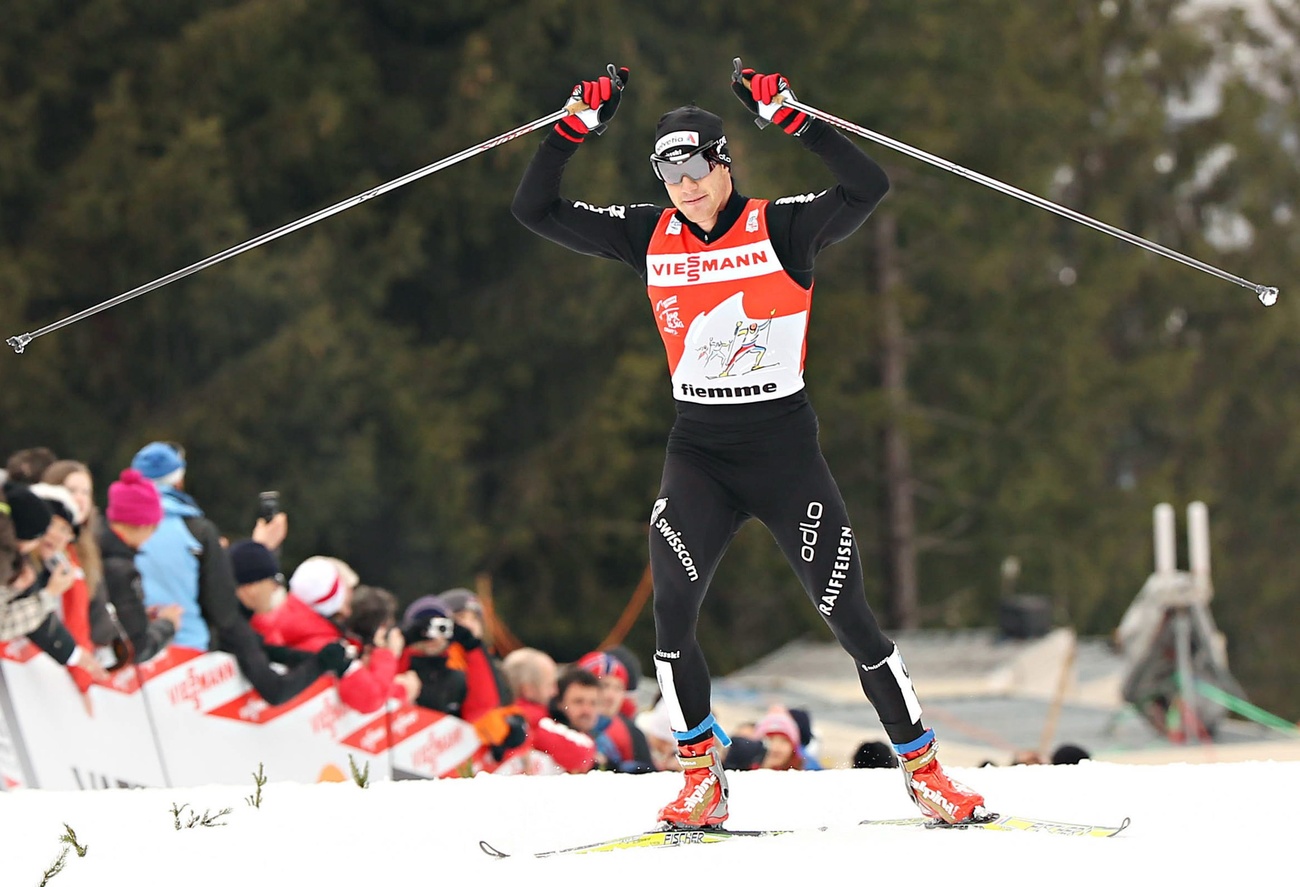 Dario Cologna alza le mani al cielo per una sua ennesima vittoria.