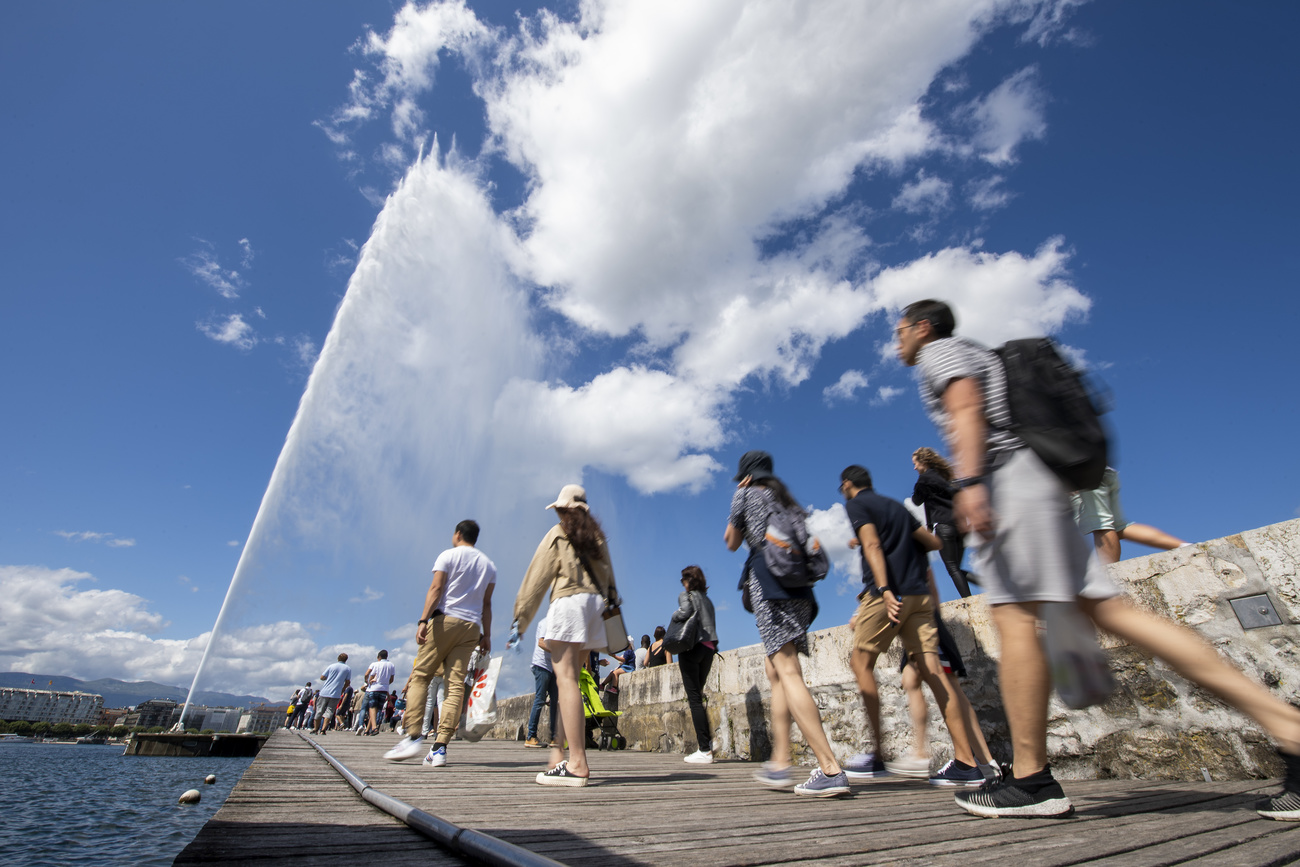 gente che cammina sulla passerella che porta al jet d eau sul lago di ginevra