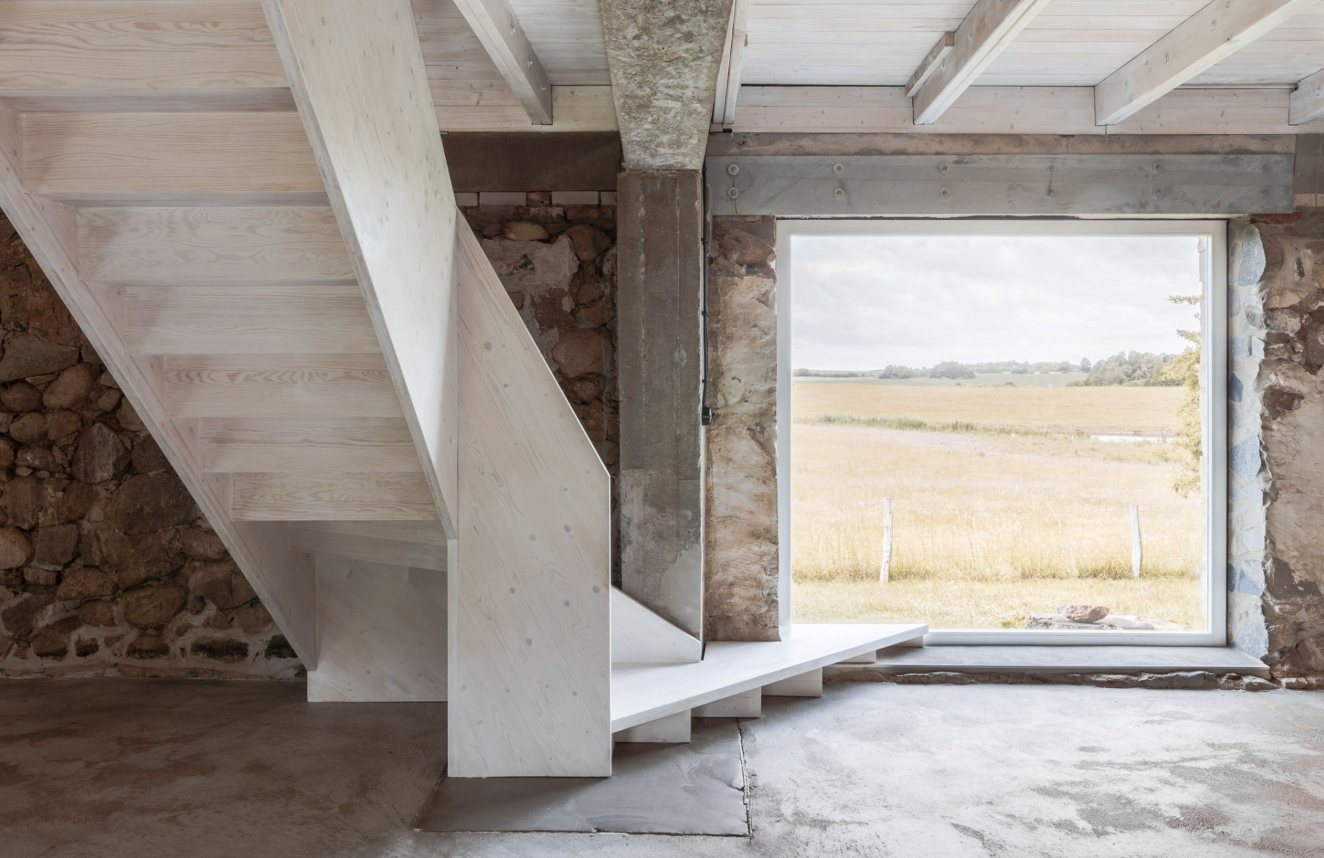 Escalier et fenêtre à l intérieur d un bâtiment agricole transformé.