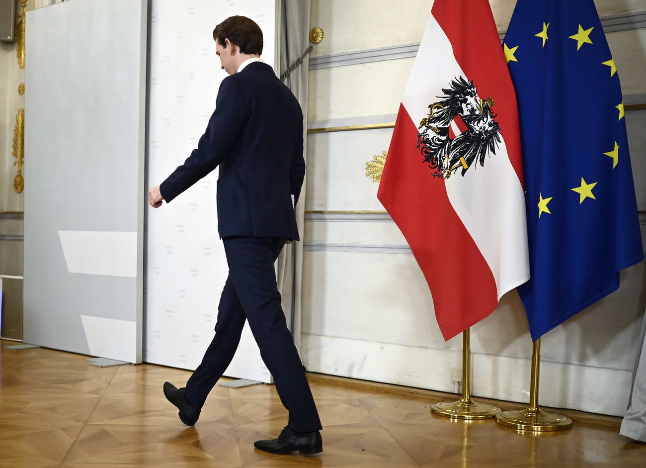 uomo che cammina in una sala in cui ci sono le bandiere dell austria e dell ue