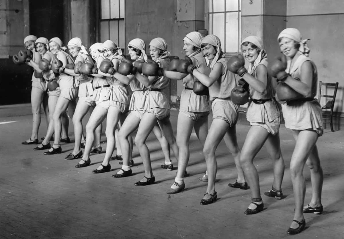 Grupo de mujeres con vestimenta y guantes de boxeo.