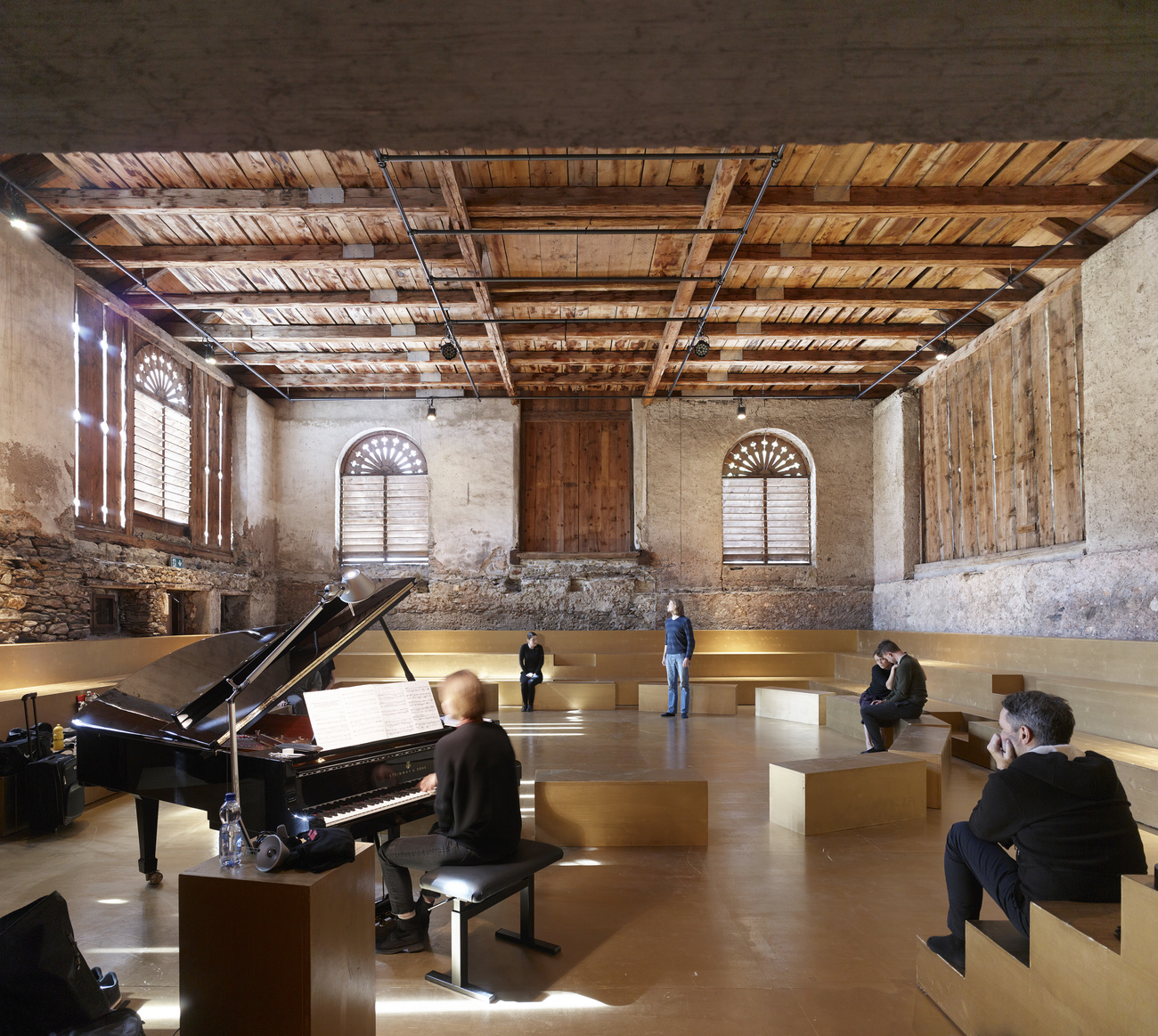 Piano et sièges dans une ancienne grange transformée en salle de spectacle.