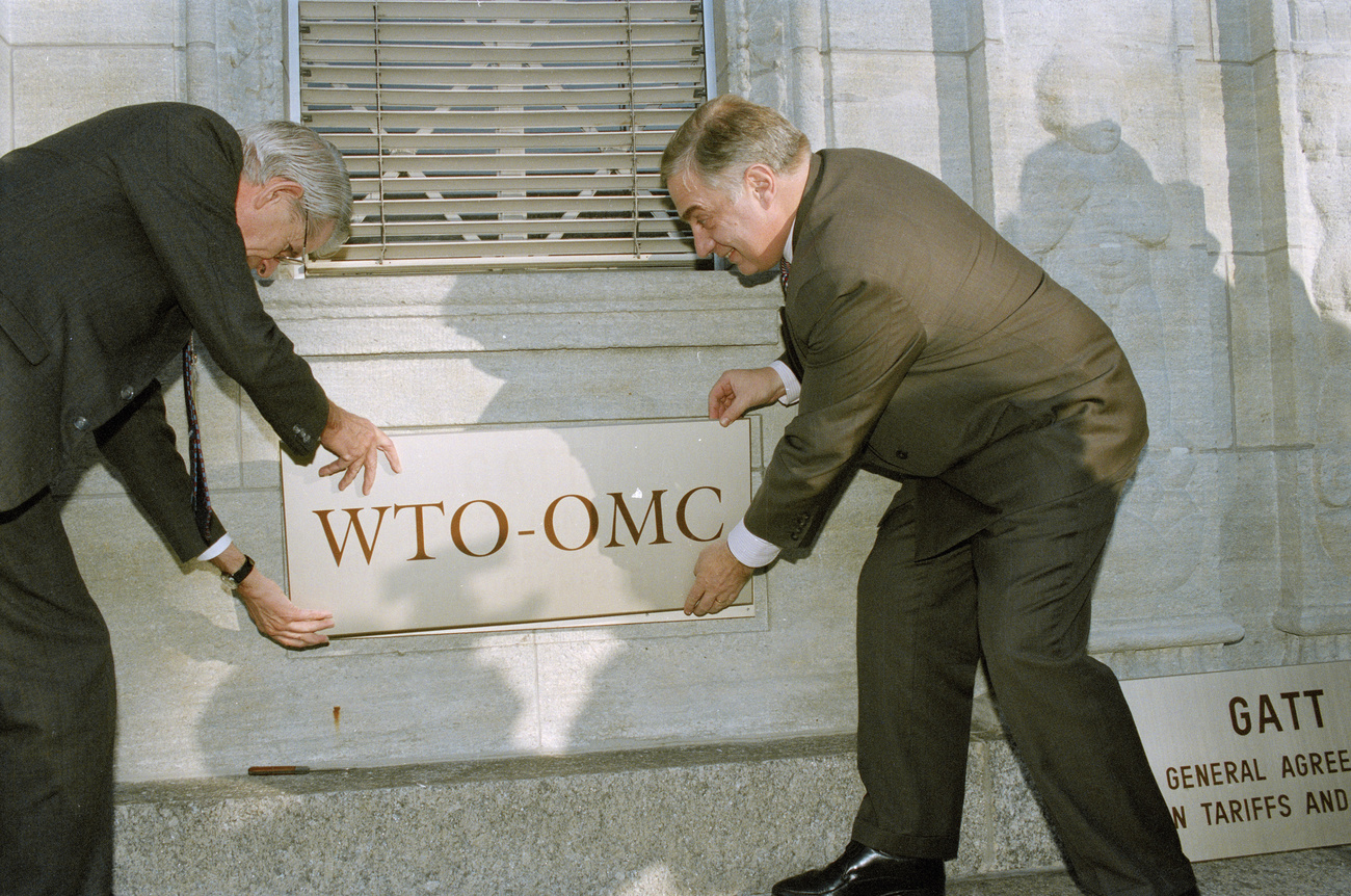 Deux hommes posent la plaque de l Organisation mondiale du commerce.