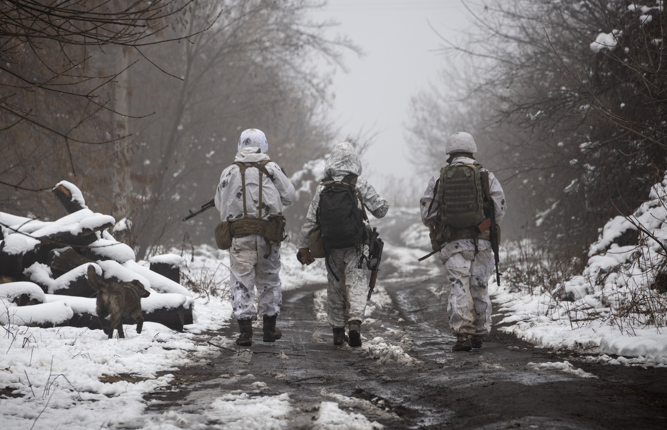 tre soldati in tenuta mimetica invernale fotografati di spalle mentre camminano
