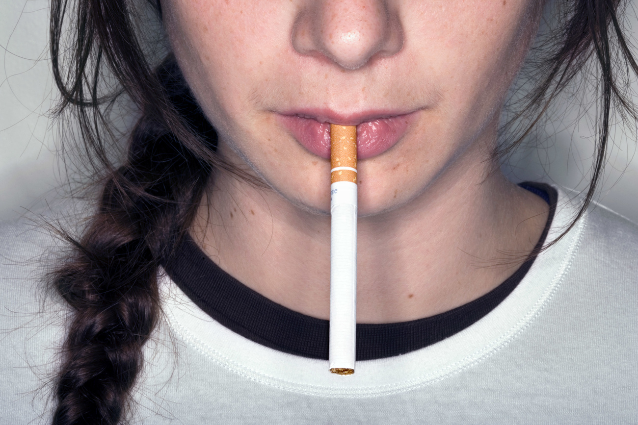 Une jeune femme fume une cigarette