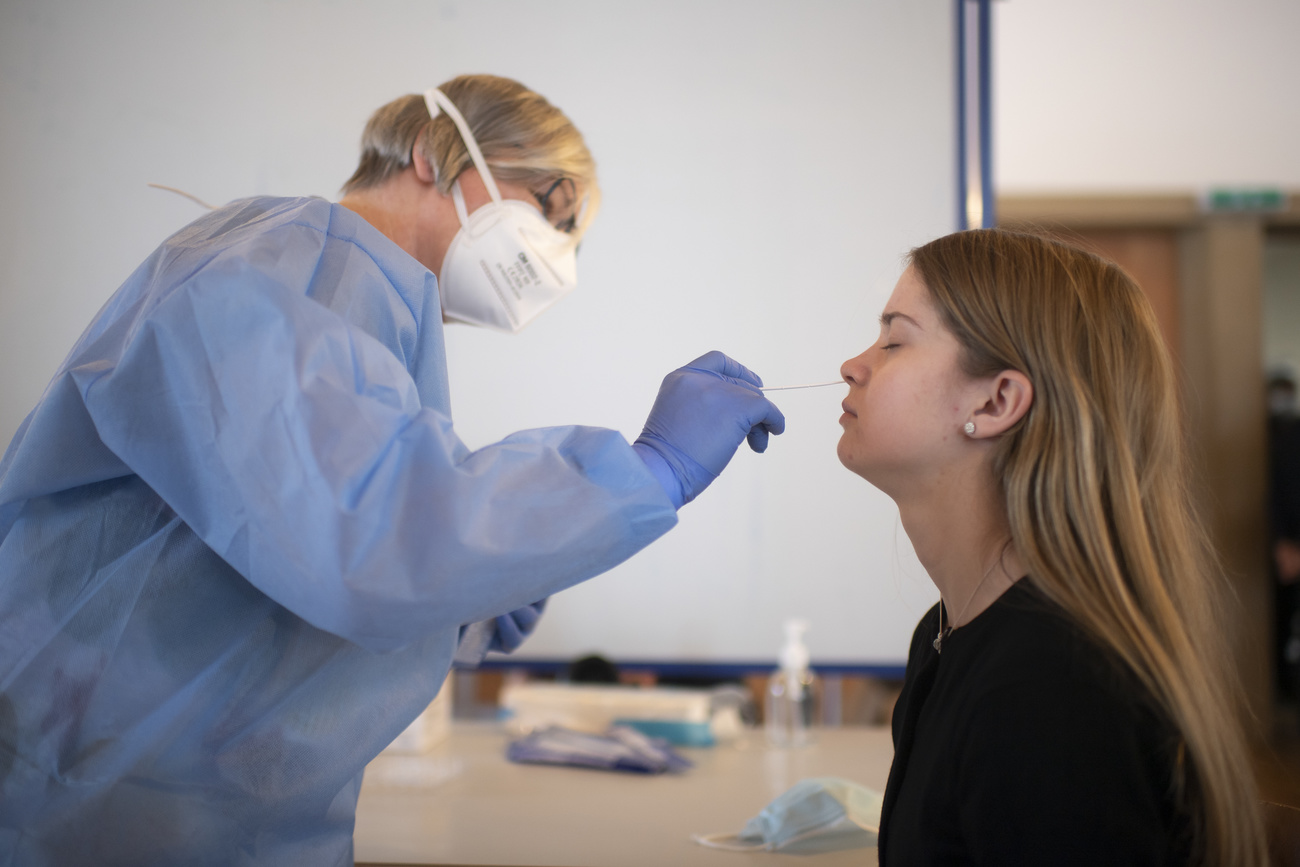 Una sanitaria introduce un hisopo en la nariz de una joven durante una prueba de detección de la COVID
