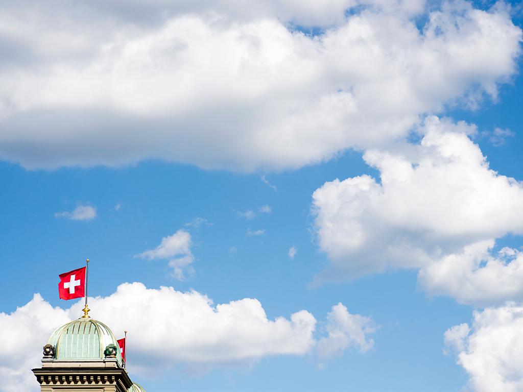 cupola di palazzo federale su cui sventola una bandiera svizzera