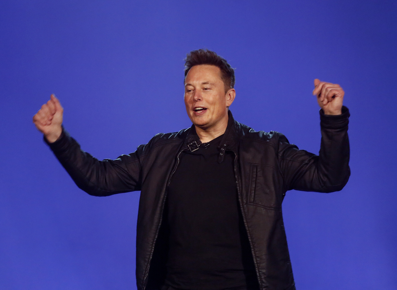 Primo piano di Elon Musk con le braccia alzate in segno di vittoria.
