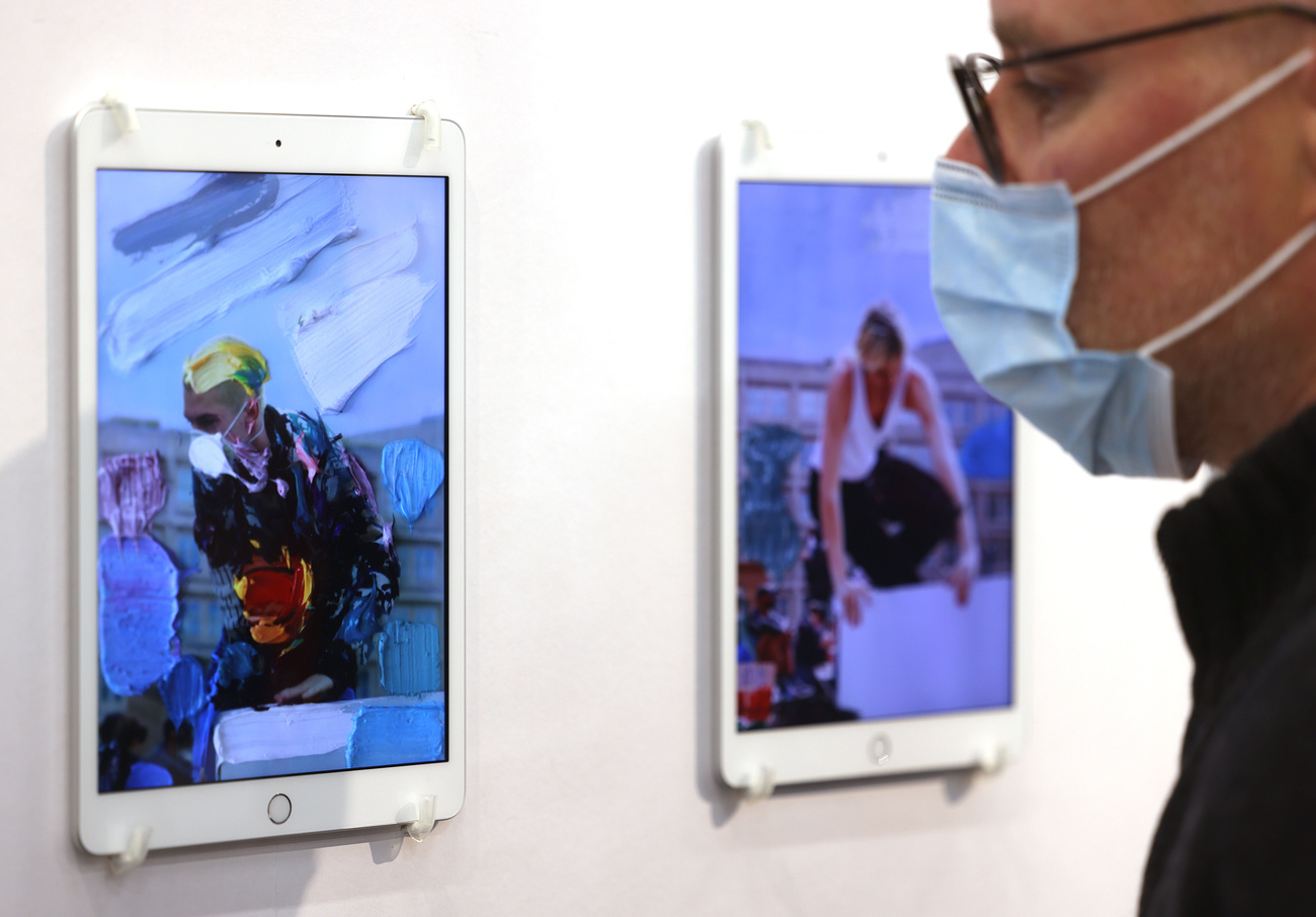 Man looking at NFTs on display on tablets hanging on the wall