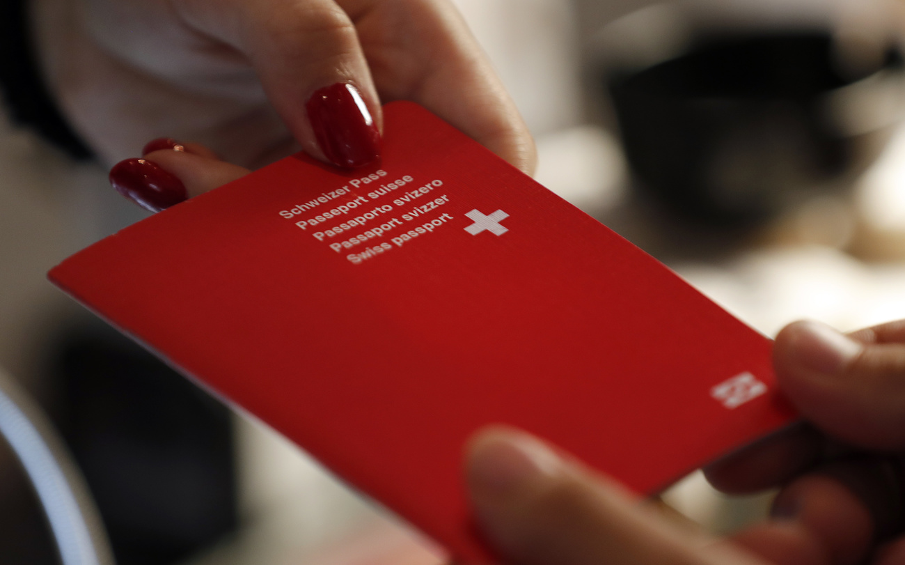 primo piano di un passaporto svizzeroche viene passato da una mano di donna a una mano di uomo