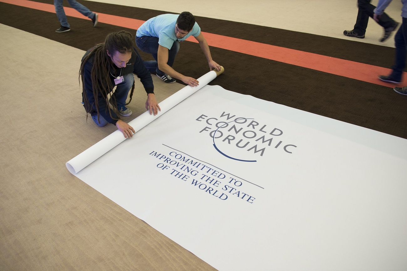 Two men roll up a World Economic Forum banner