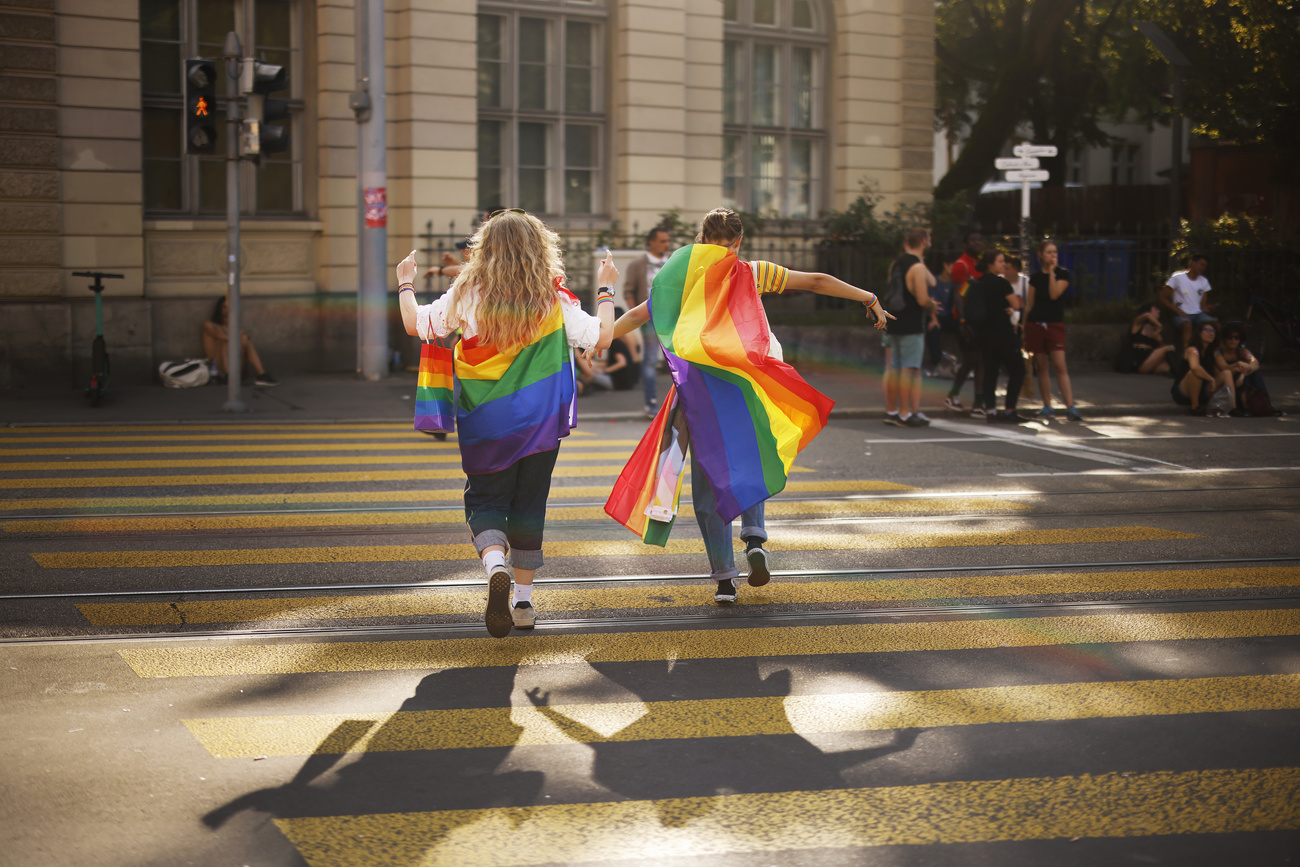 Pareja con la bandera multicolor cruzando la calle