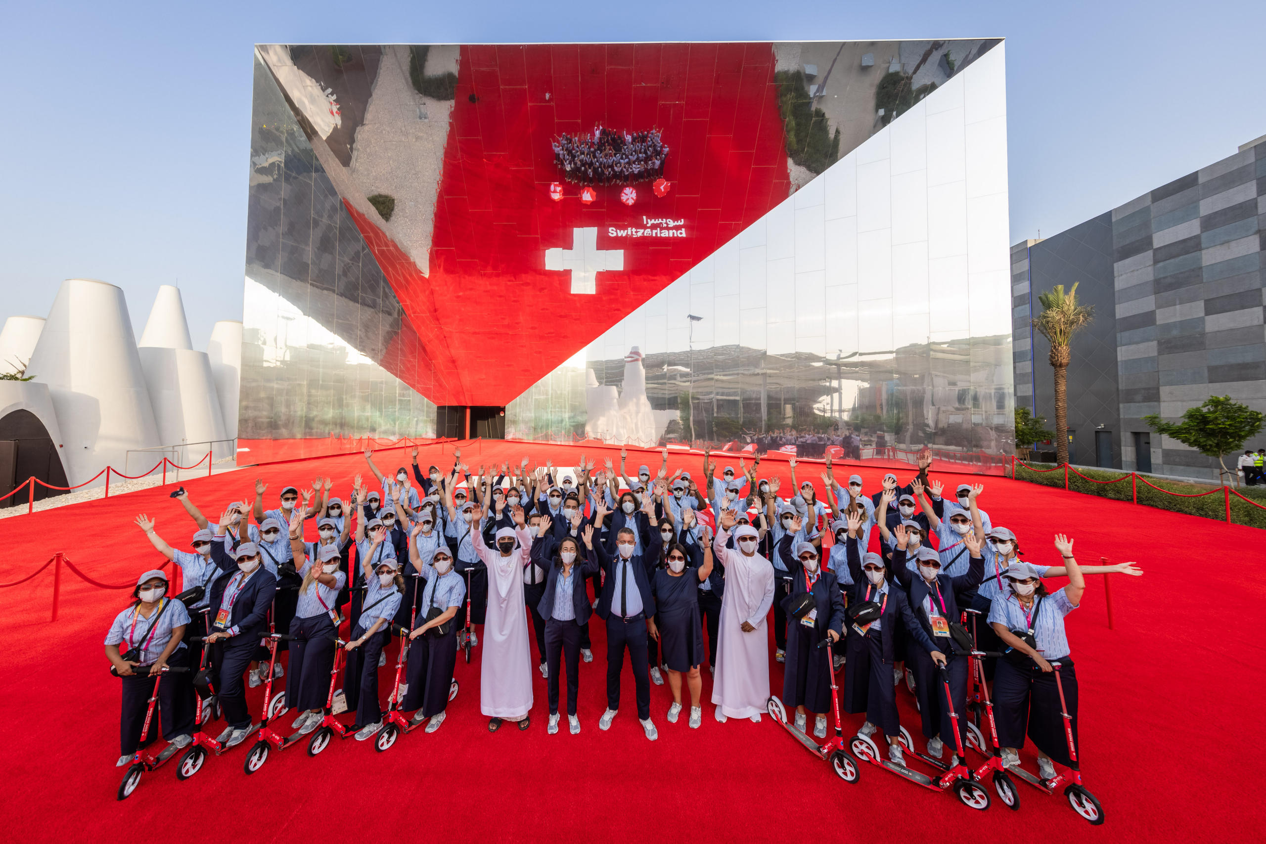 Building reflecting the Swiss Flag in a Mirror with a Crowd in front