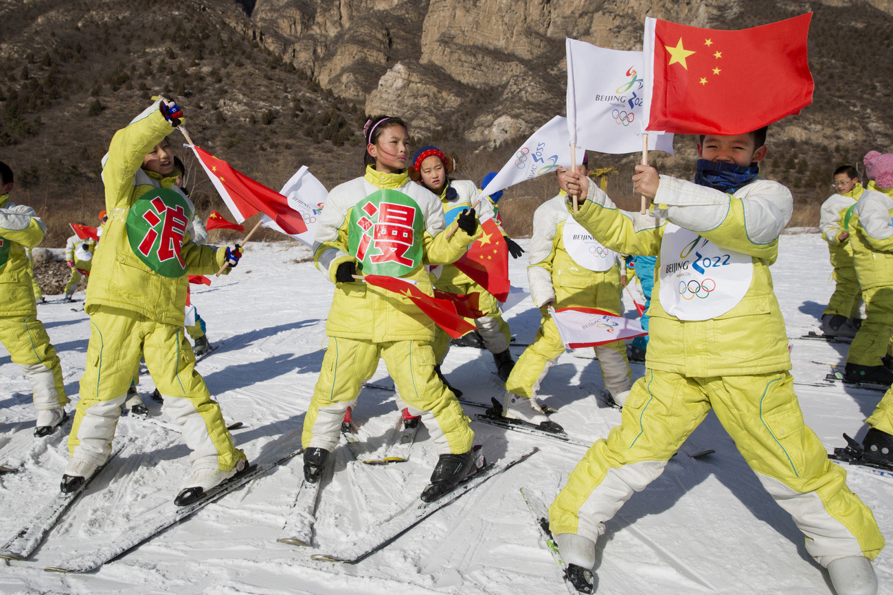 Alumnos de una escuela china de esquí ondeando banderas.