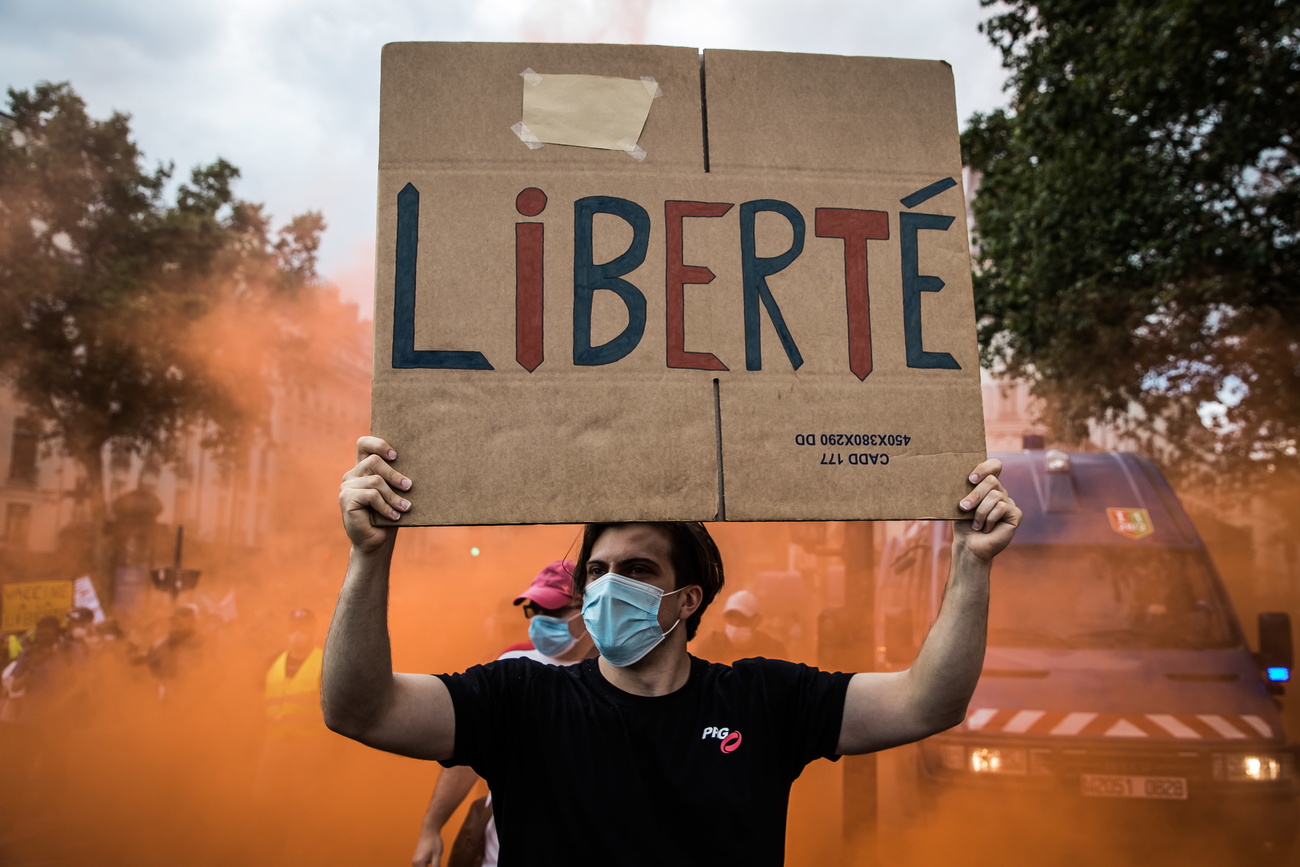Durante una protesta contro le misure anti Covid a Parigi un uomo con un cartello con scritto Liberté