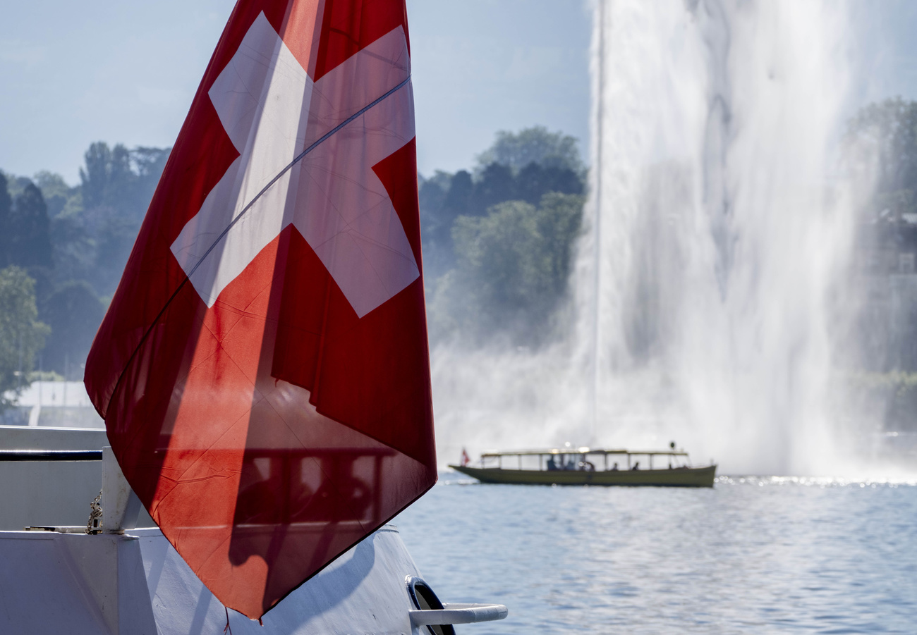 Swiss flag with jet d eau in Geneva in background.