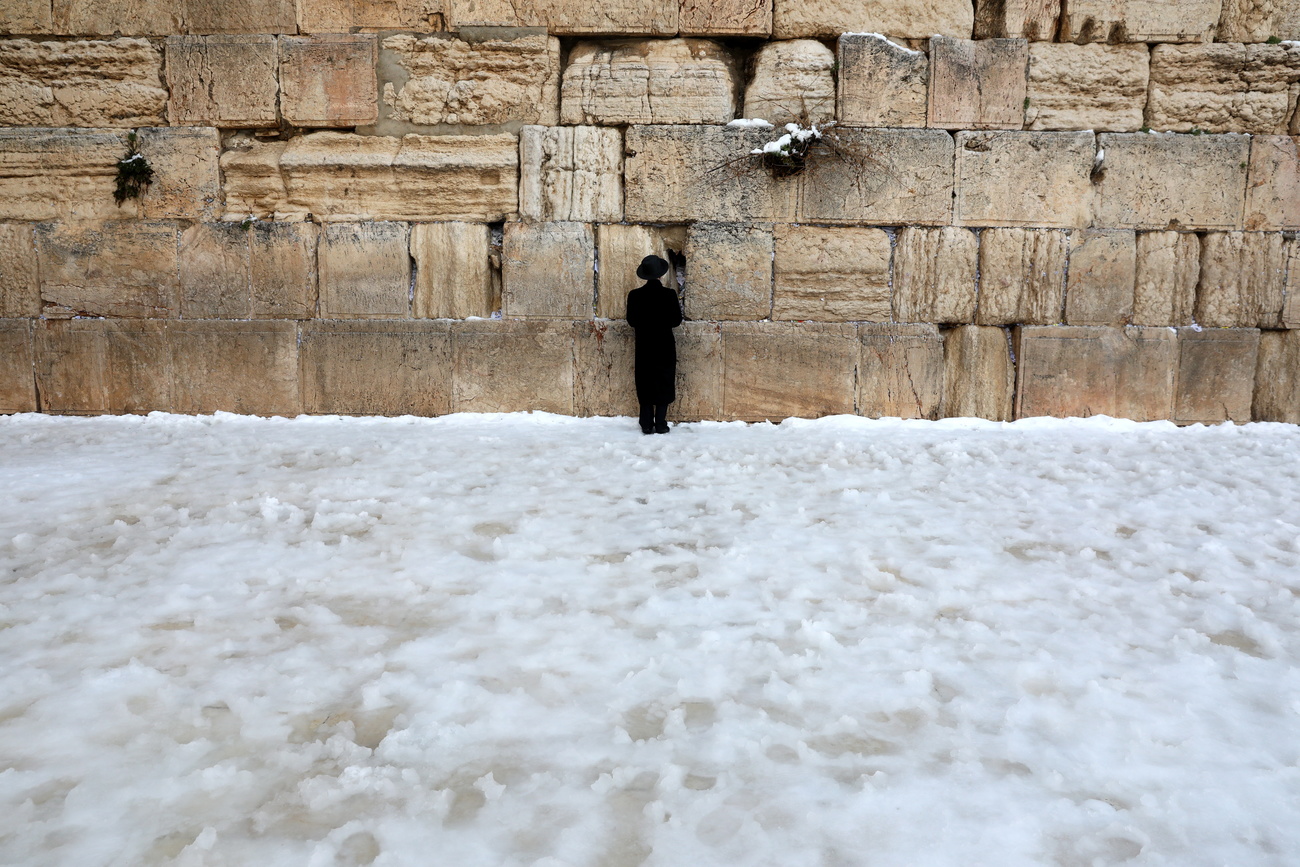 Un uomo prega davanti al muro del pianto di Gerusalemme e tutt intorno solo neve.