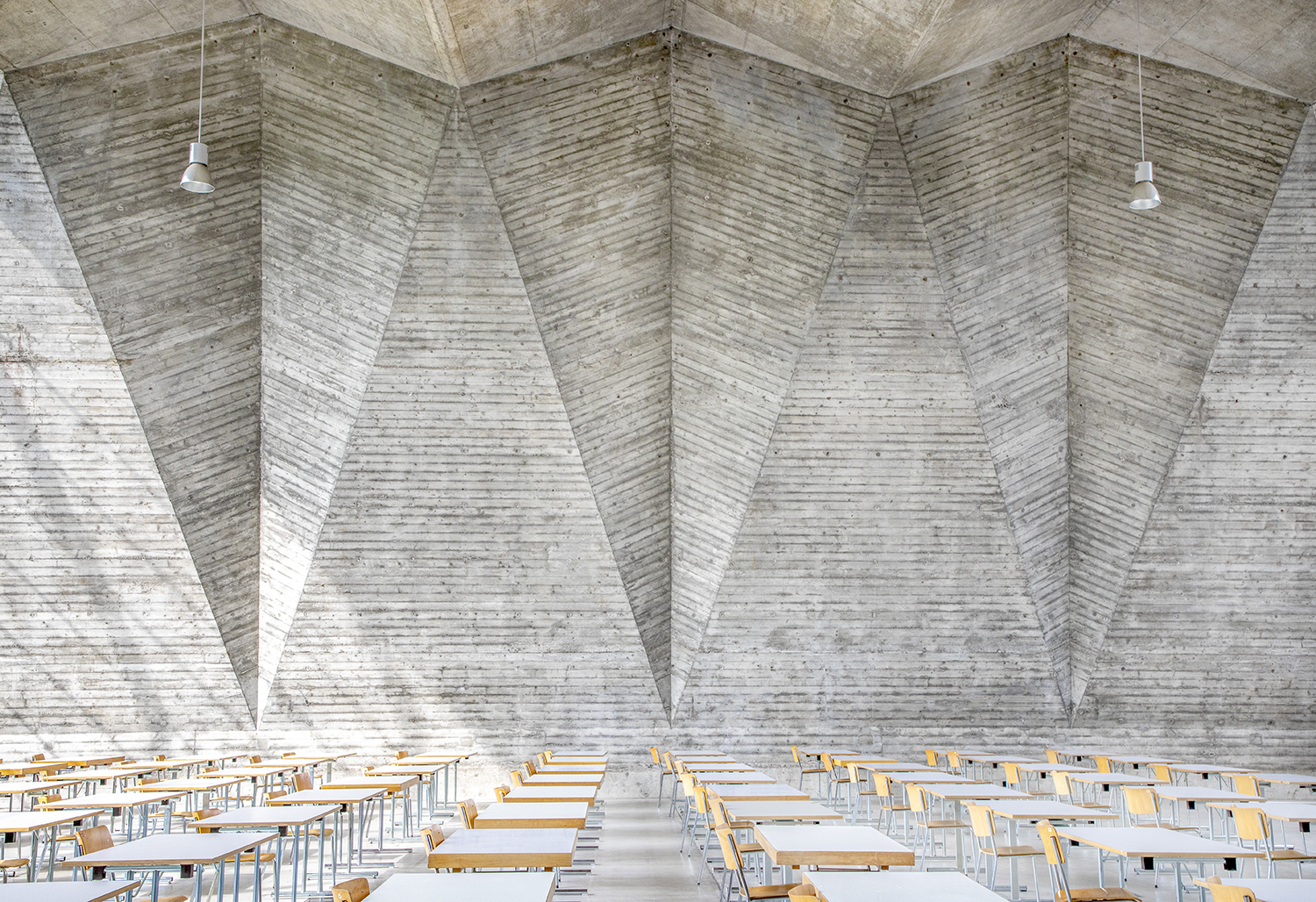 Un comedor con grandes paredes de hormigón con formas geométricas