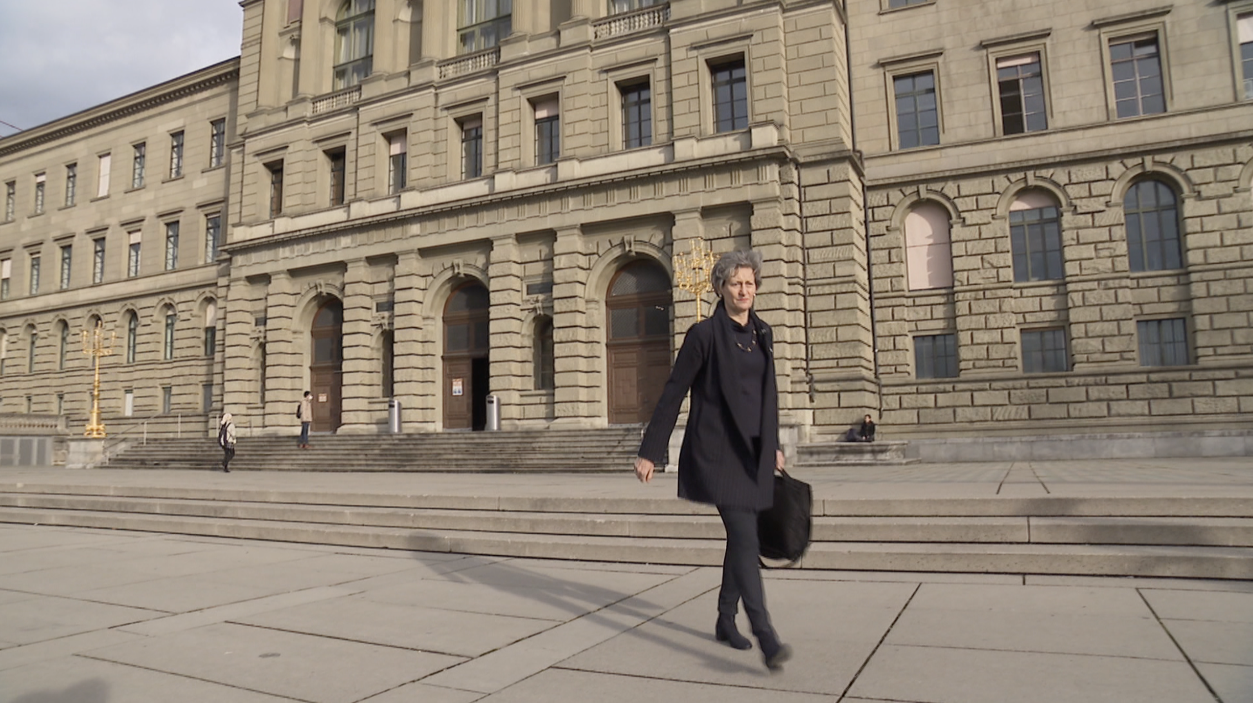 امرأة تغادر مبنى مؤسسة جامعية في زيورخ