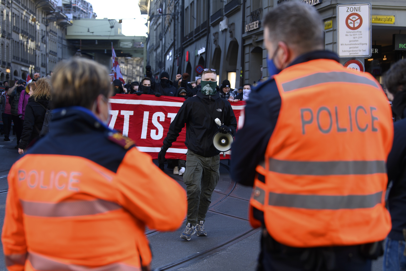 Two members of police facing far-right protestors in streets of Bern