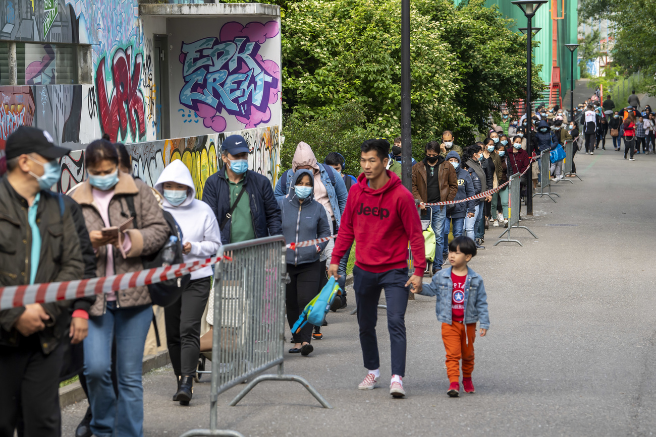 Man with young child walking past people queuing for food