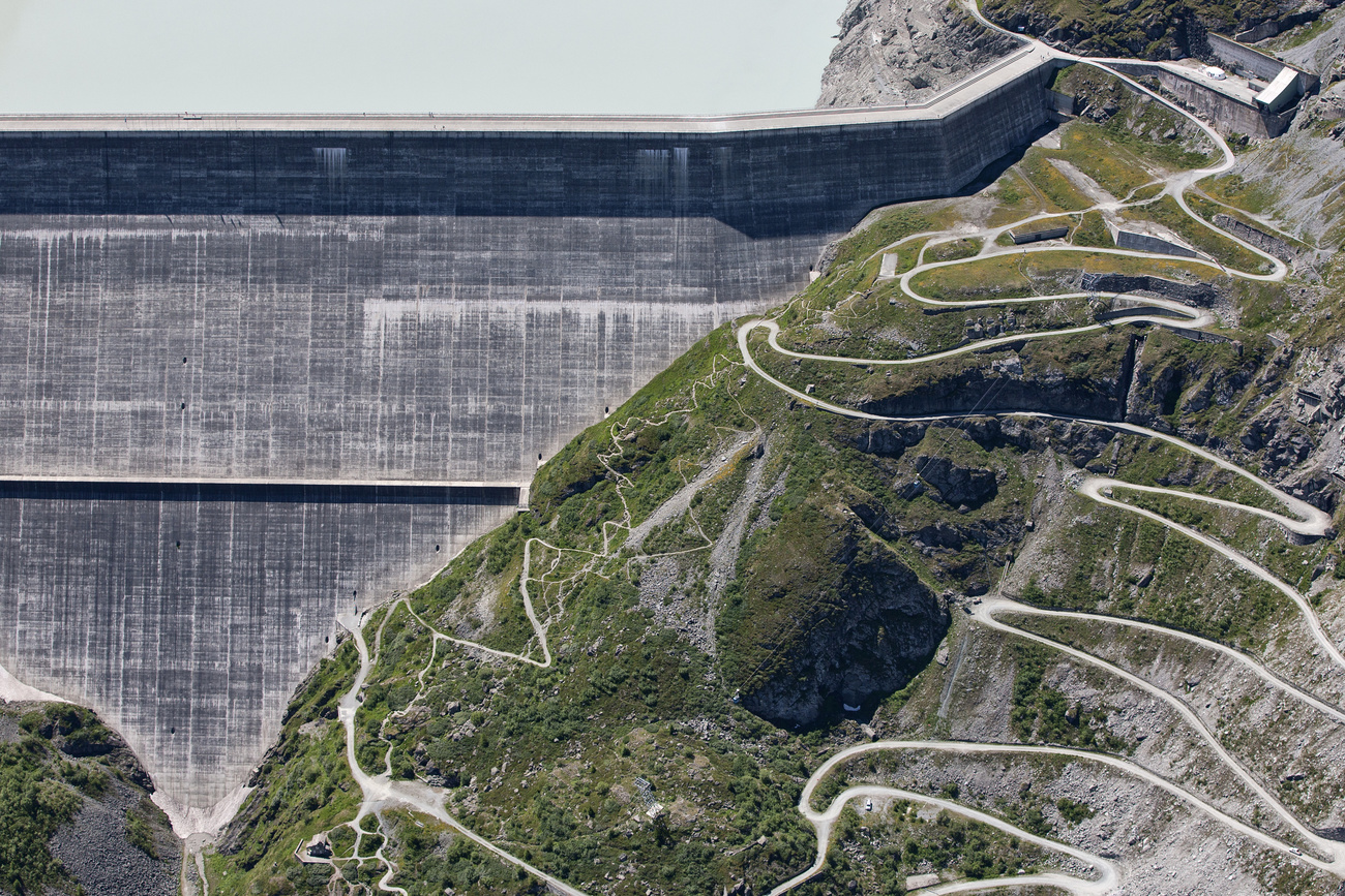 Swiss dam with hill in foreground.
