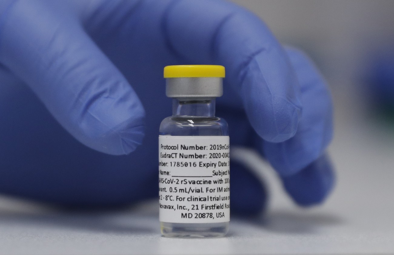 Hand with surgical glove holds a Nuvaxovid vial