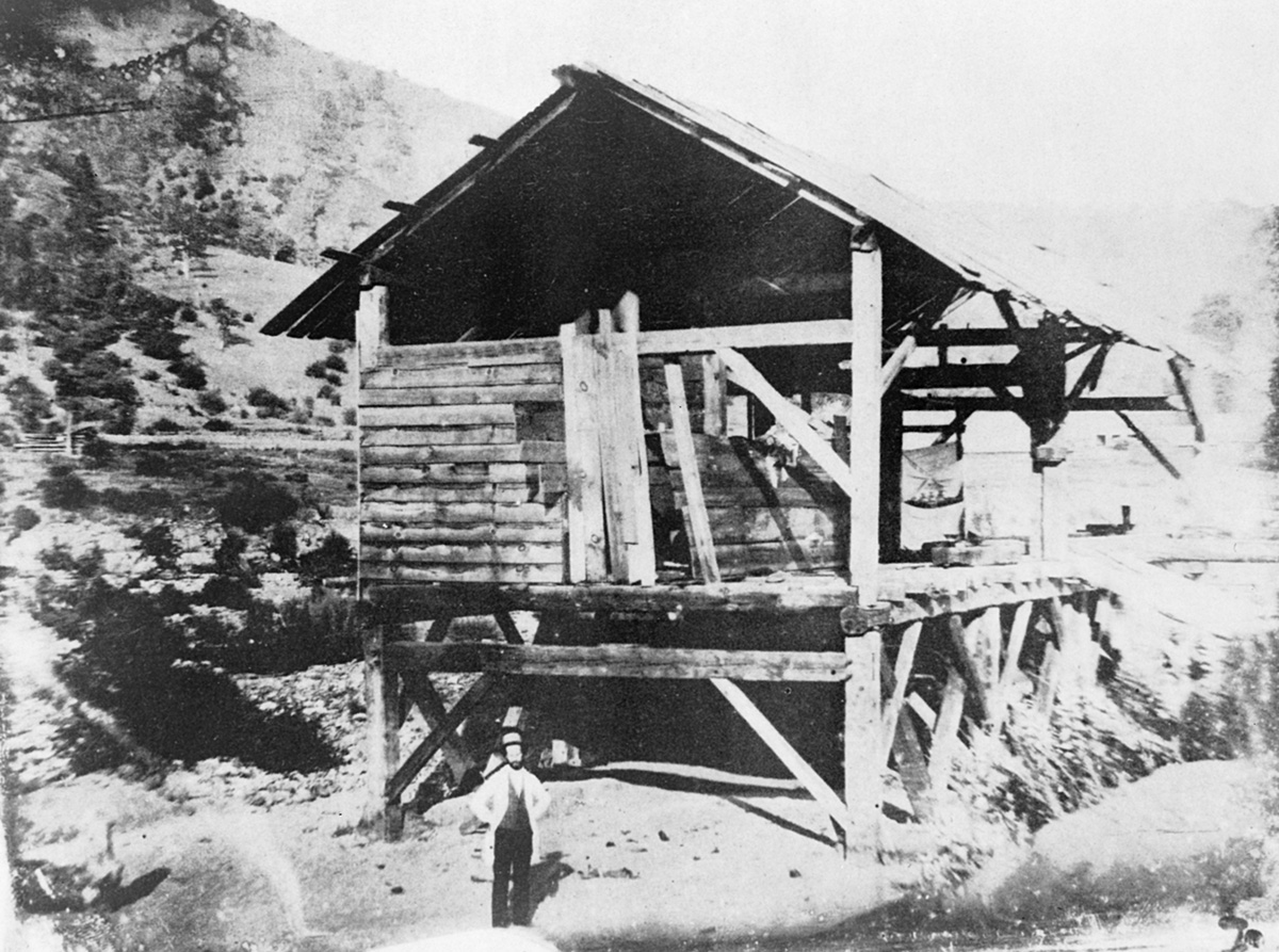 Altes Foto, das einen Mann vor einer Hütte zeigt