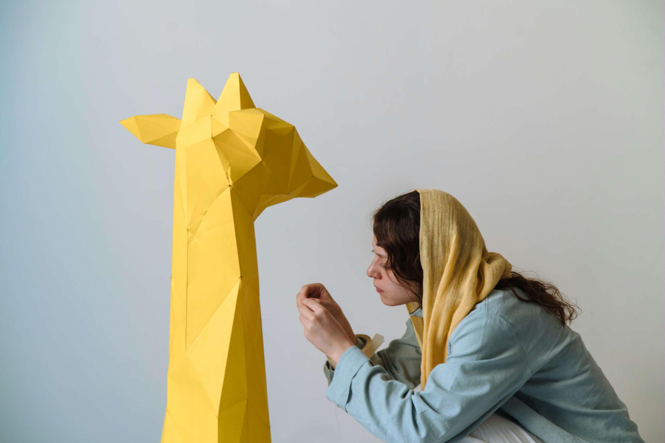 Escena de Spottled Yellow : Una niña forma una jirafa de papel