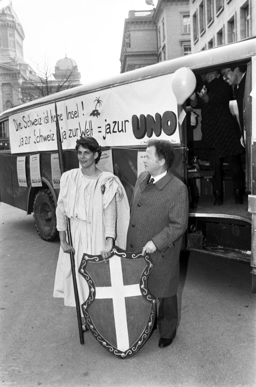 una donna vestita da helvetia e un uomo di fronte a un autobus