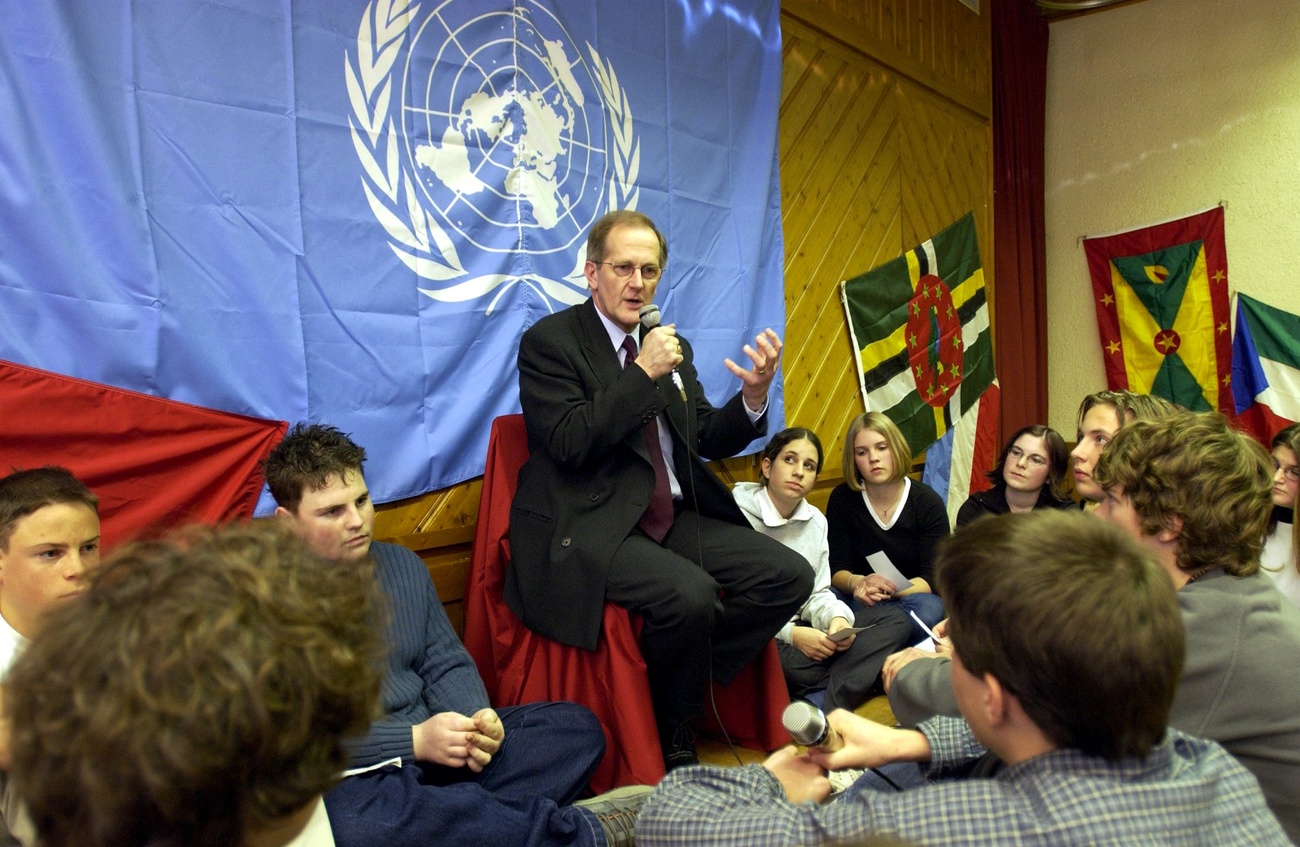 Homme parlant devant des jeunes avec un drapeau de l ONU derrière lui