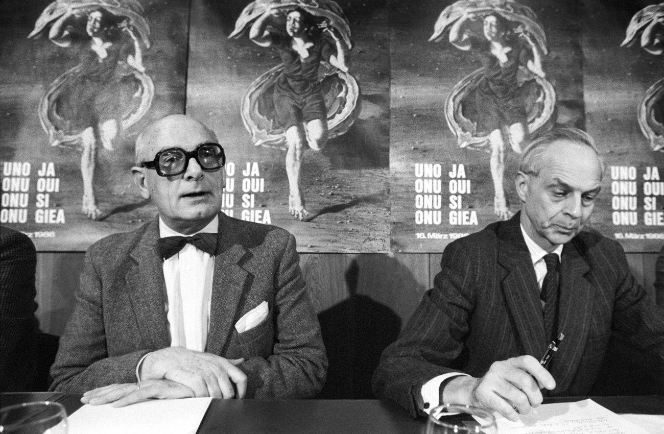 Deux hommes assis à une table devant des affiches politiques.