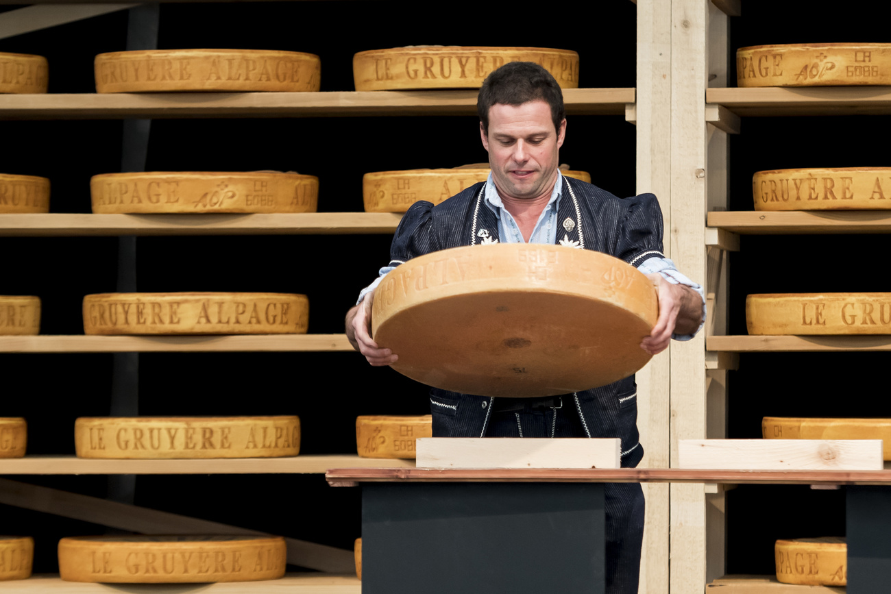 Un casaro con una forma di Gruyère tra le braccia.