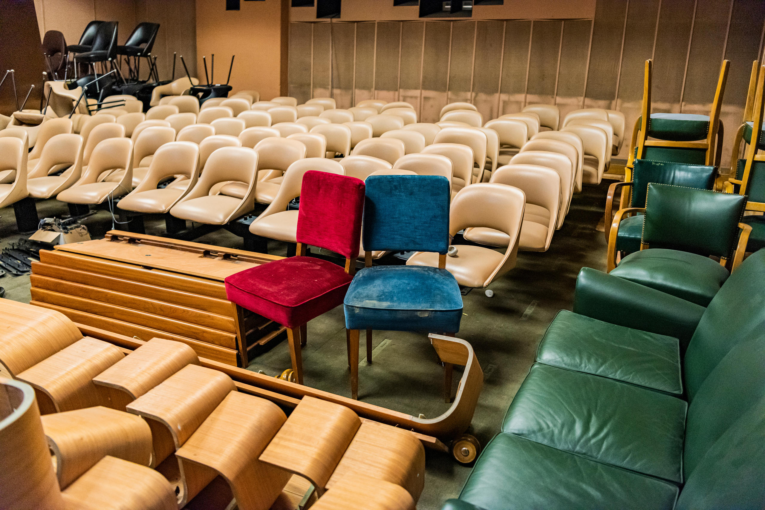 A mixed assortment of chairs stocked in a basement cinema.