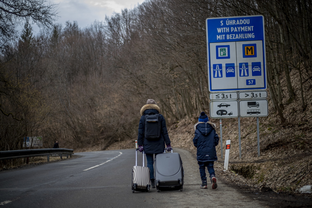 Personas caminando por una carretera, con maletas.