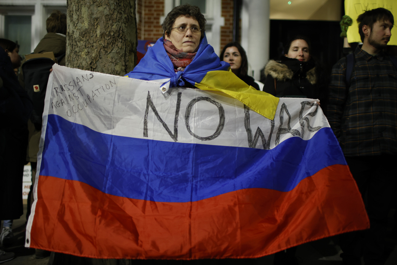 Woman protestor holds Russian flag with No war writen on it.