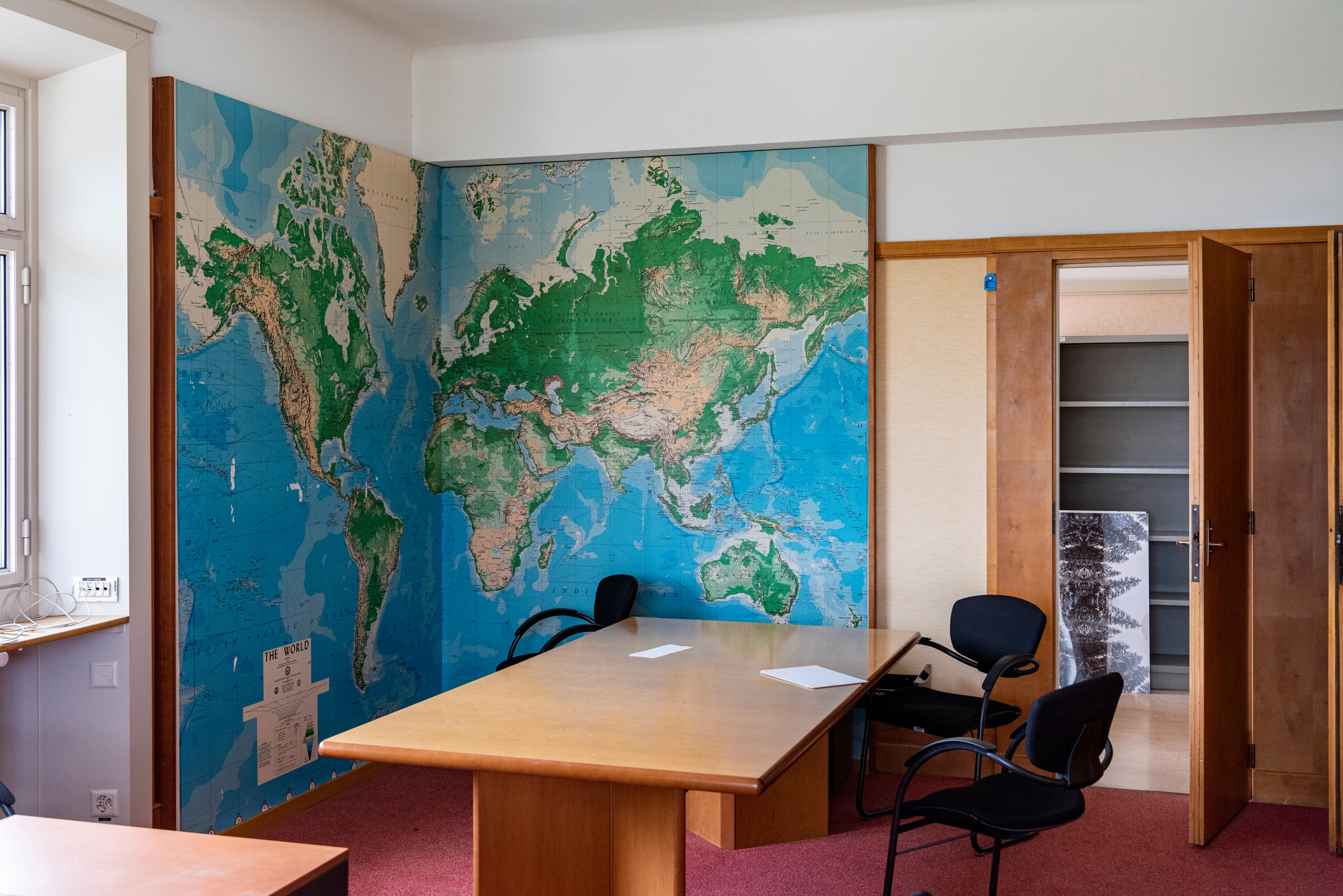 壁に大きな世界地図が飾られた無人のオフィス