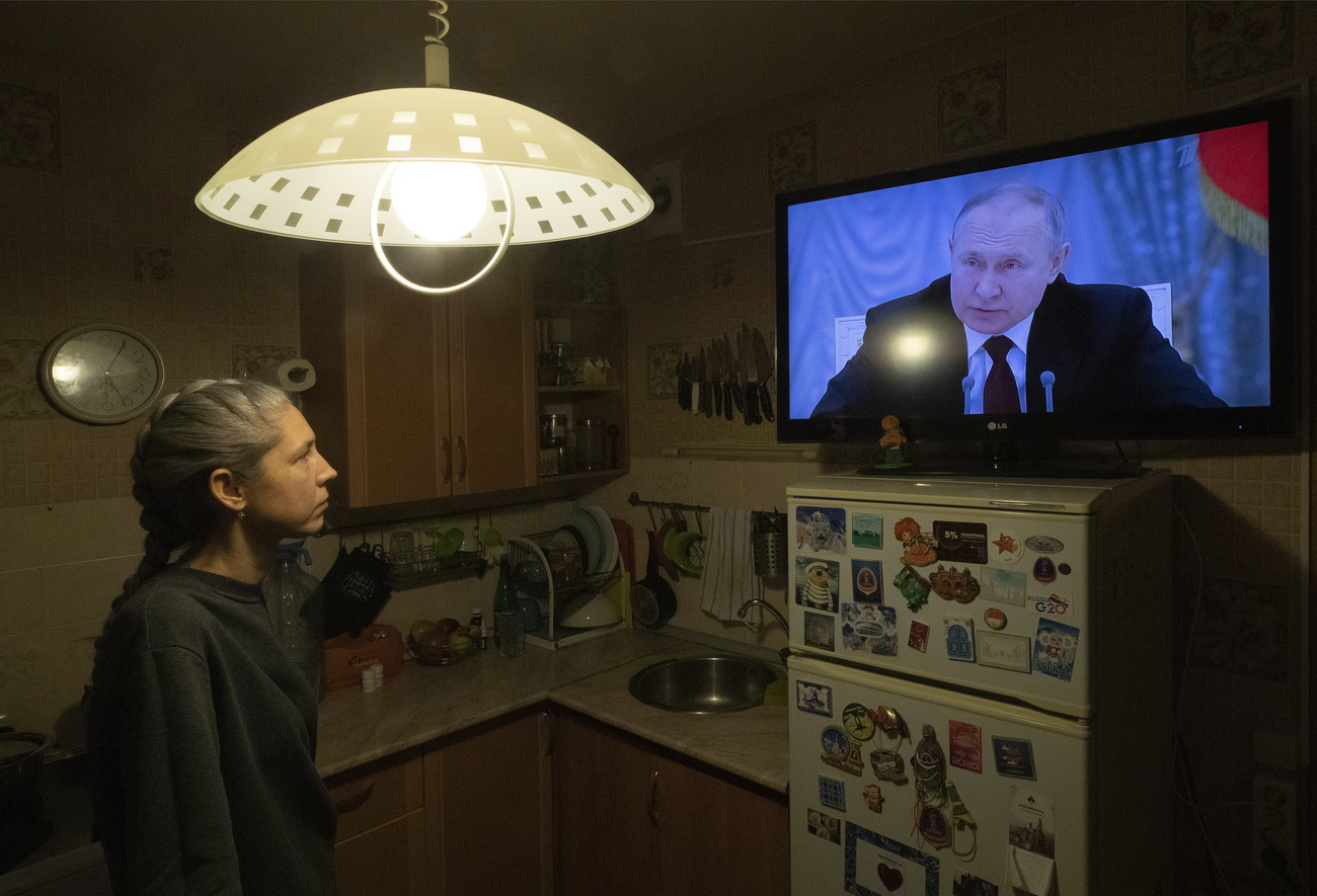 Femme regardant le président russe sur un écran de télévision