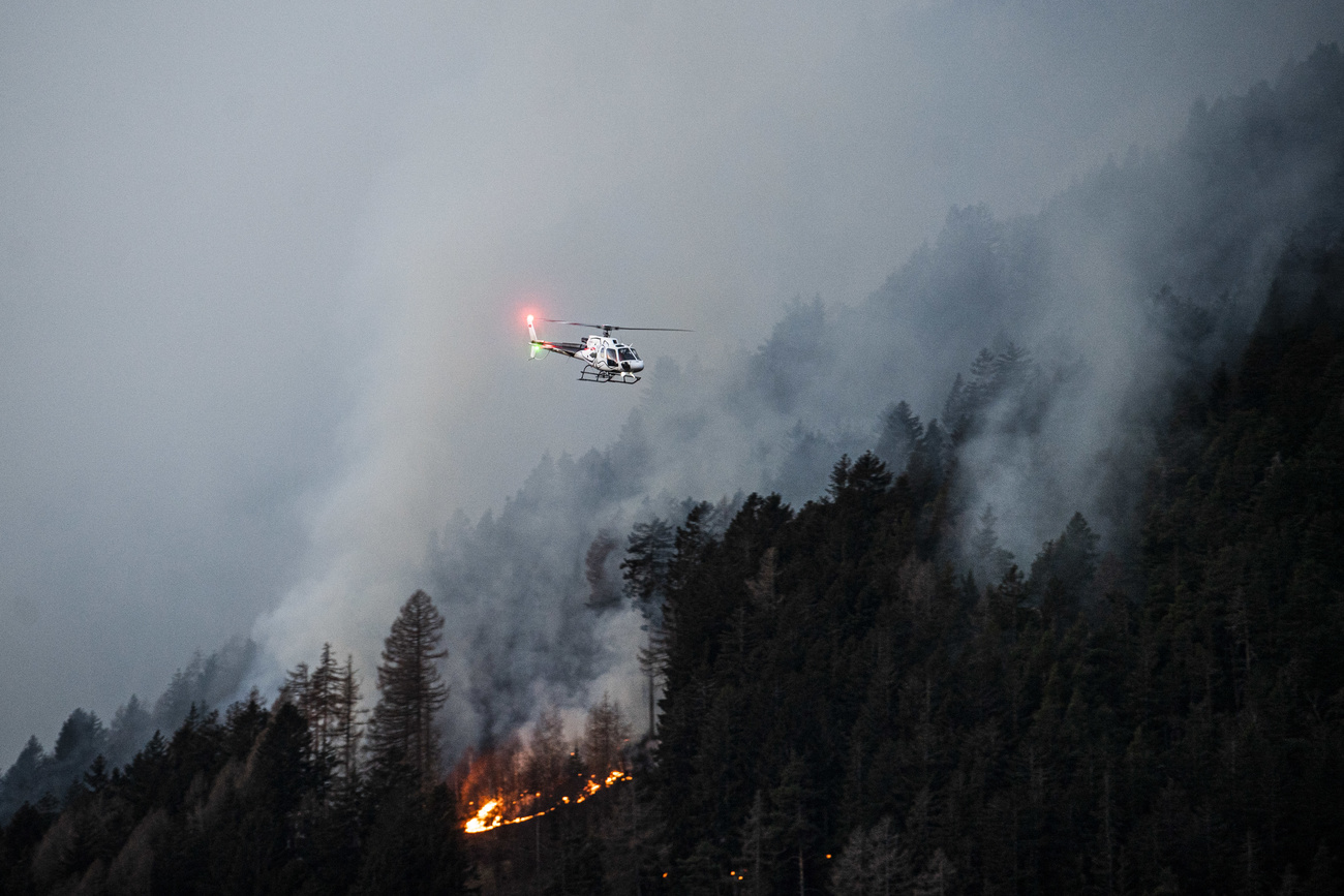 Helicóptero sobrevuela área boscosa en llamas