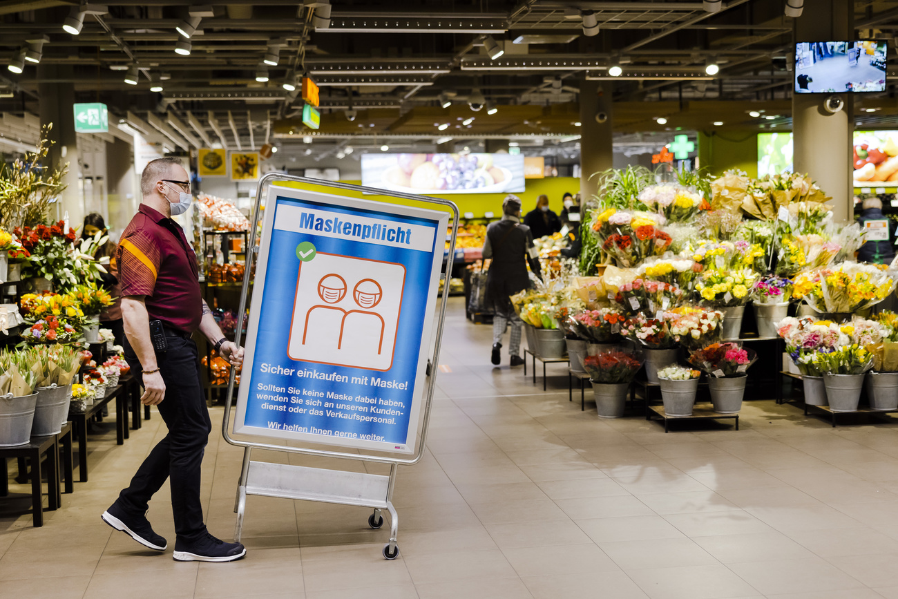 impiegato sposta un cartello con la scritta obbligo di mascherina