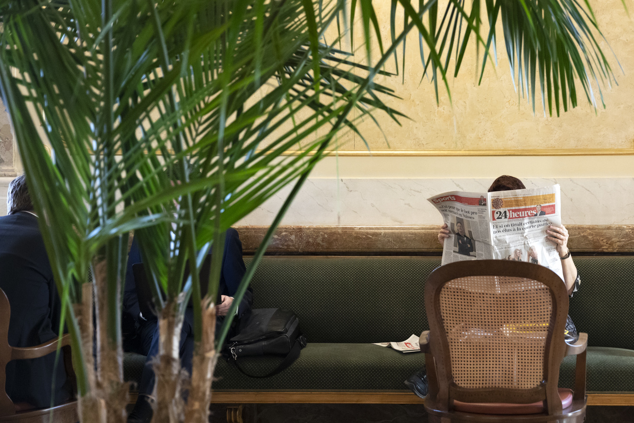 An MP reading a French-language newspaper in the lobby of parliament