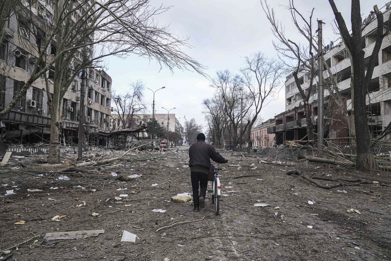 Man walks through devastated street of Mariupol.