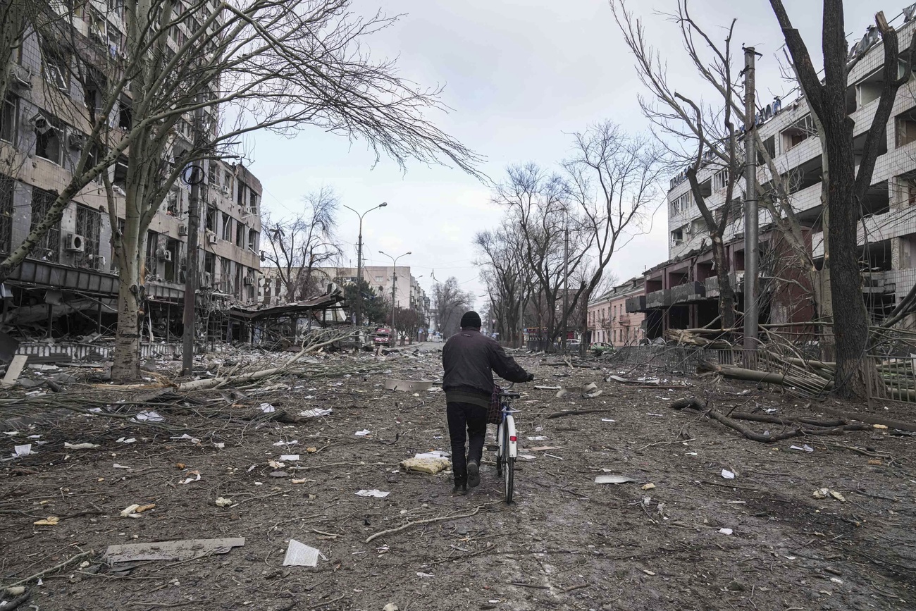 Homem caminha pela rua devastada de Mariupol.