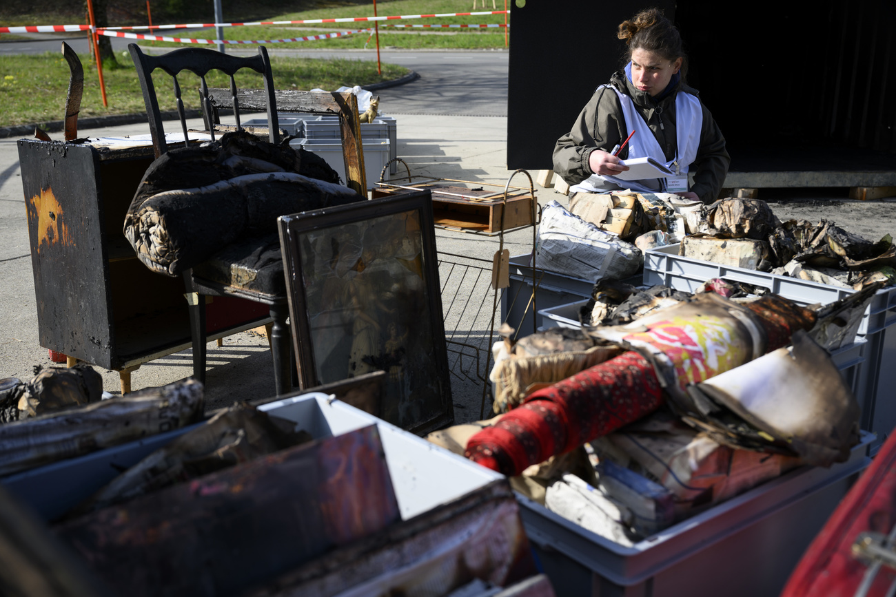 Femme devant des objets calcinés.