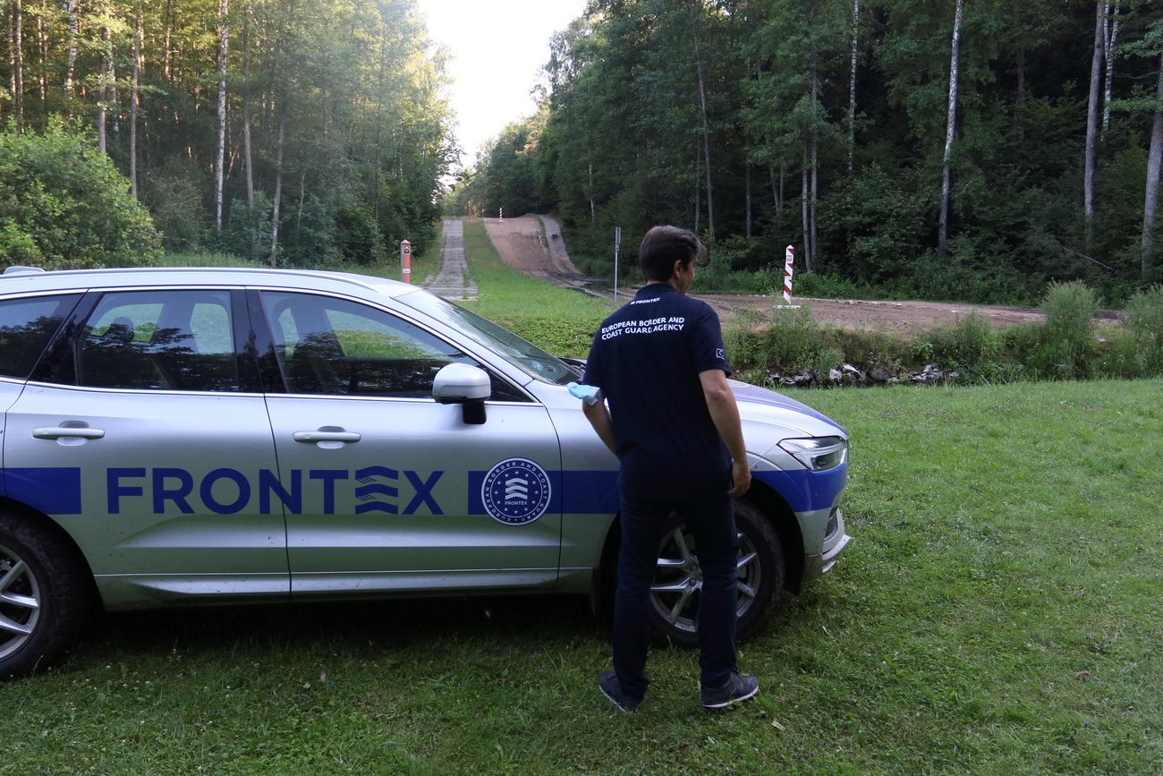 Un guardia de Frontex junto a su vehículo cerca de un camino carretero