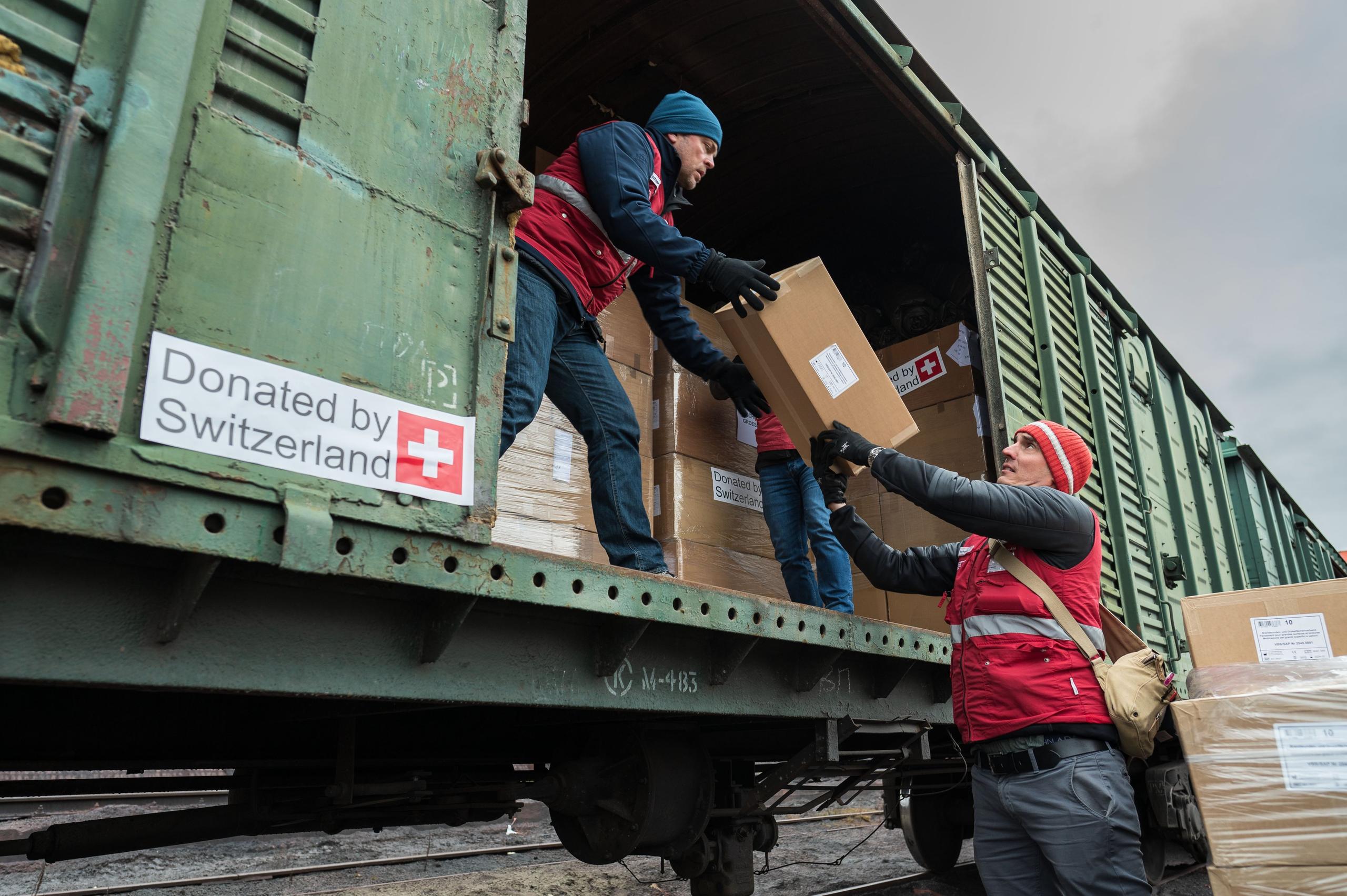 Trabajadores cargando la ayuda suiza humanitaria en un tren