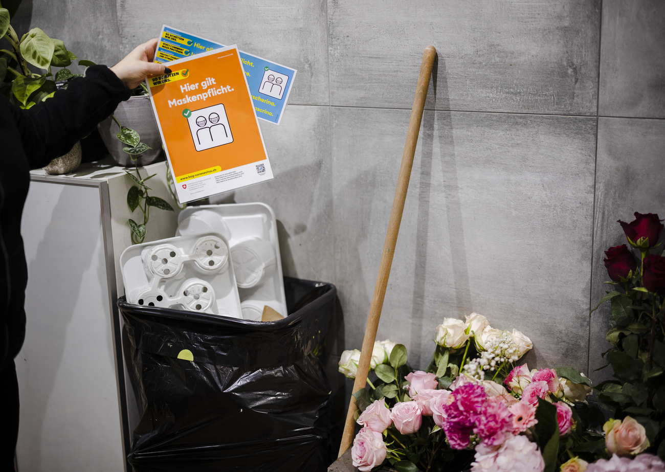 une femme met à la poubelle une affichette annonçant l obligation de porter le masque