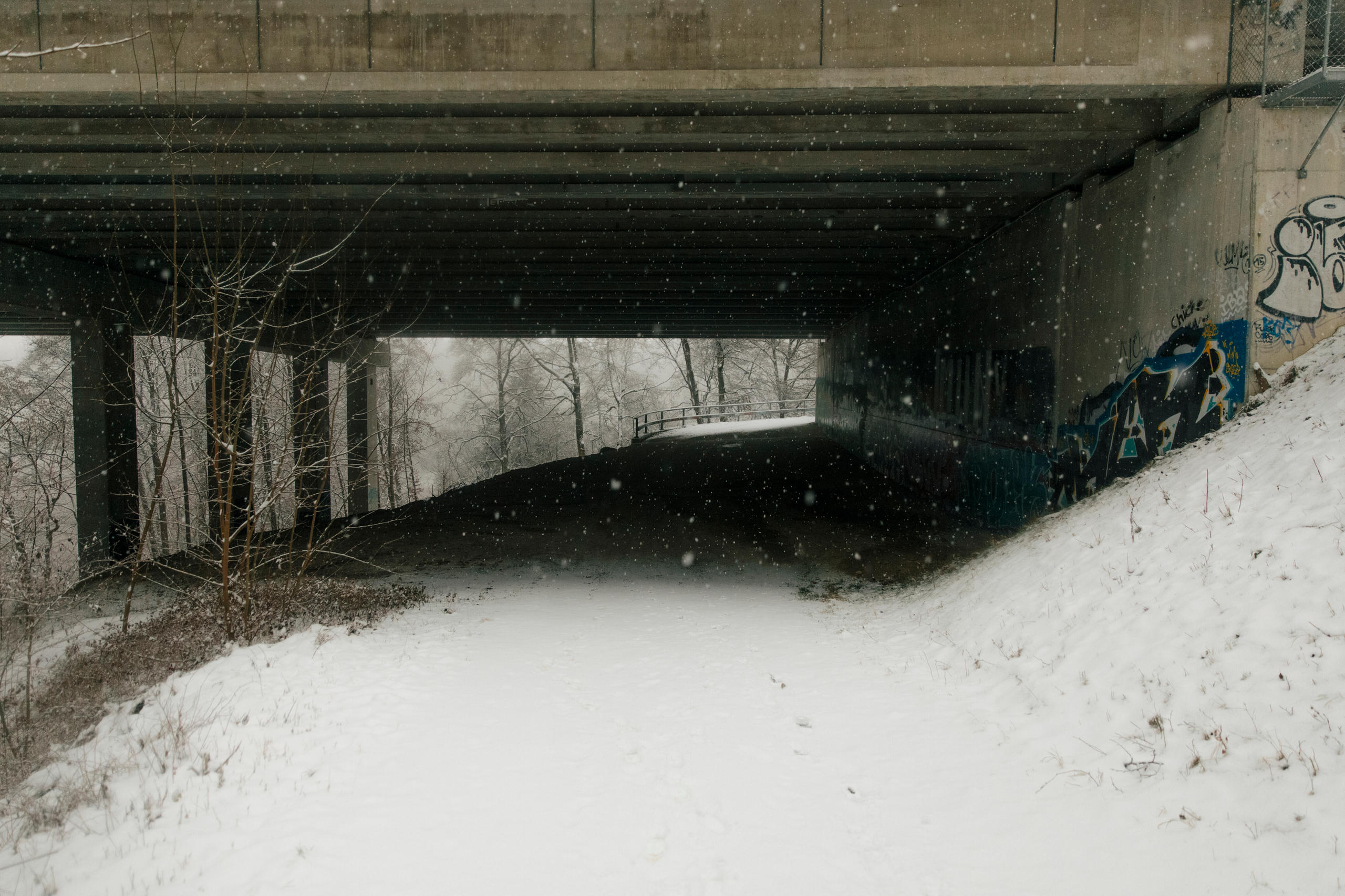 Passage enneigé sous un viaduc en béton