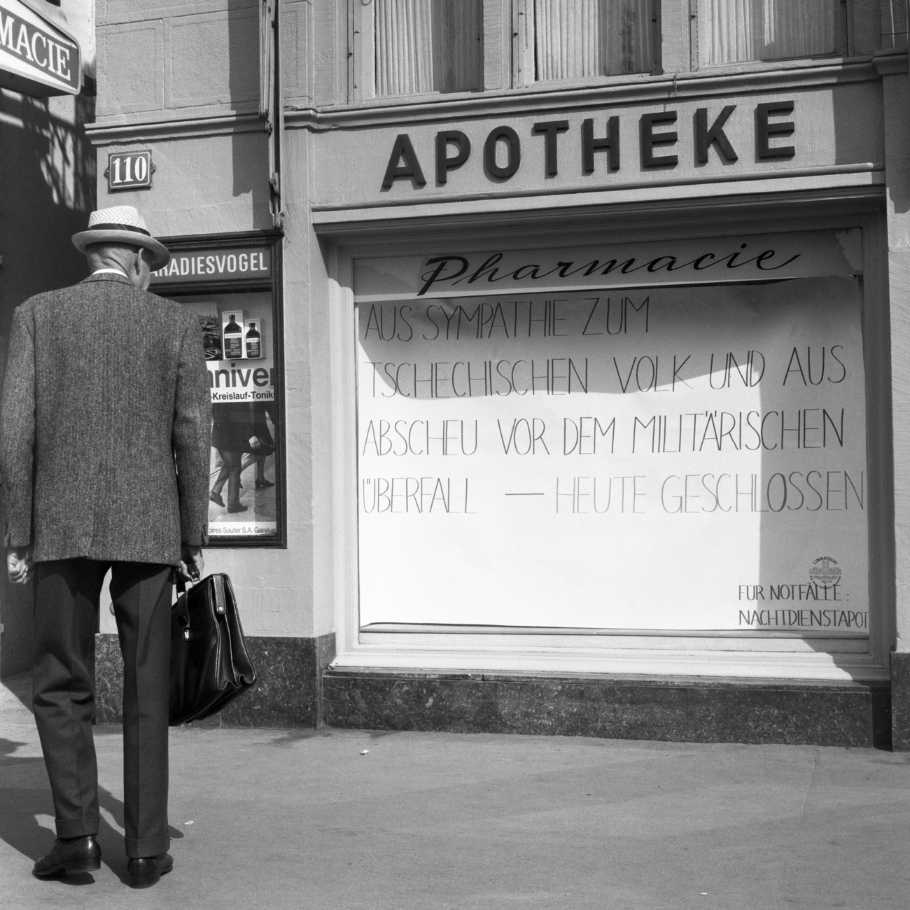 Un hombre lee una pancarta colgada en la vitrina de una farmacia