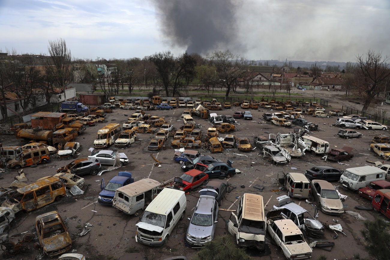 carcasse di auto. in lontananza si innalza una colonna di fumo